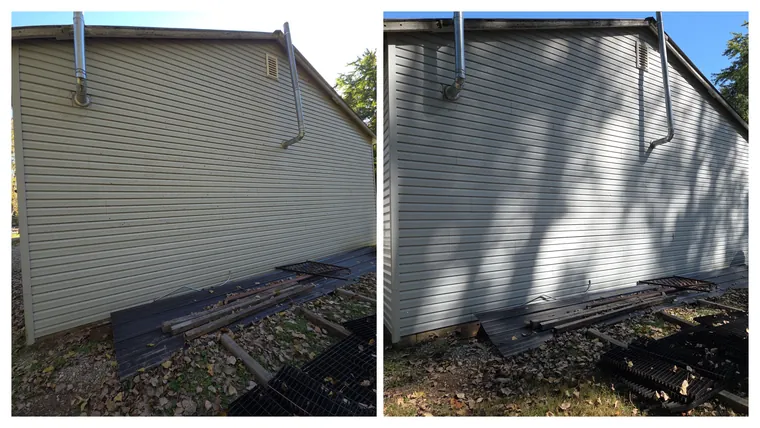 Before and after: the vinyl gable end of an outbuilding, dull film soft washed off around the flue pipe